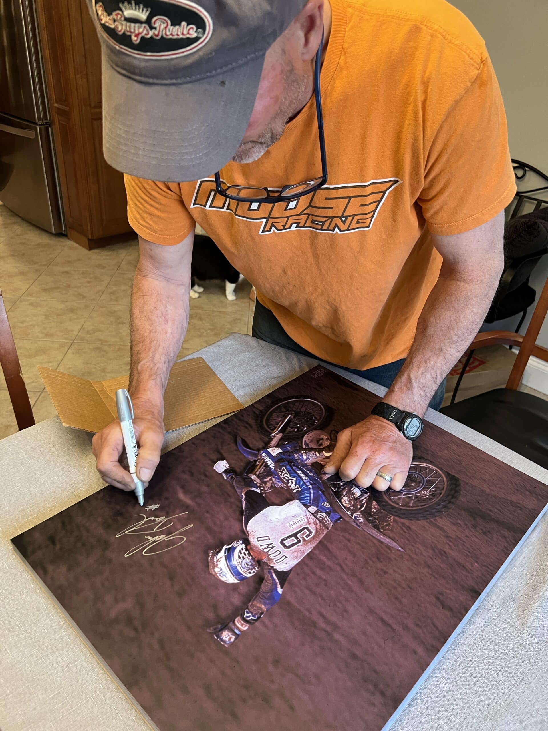 John Dowd signing Southwick 1998 prints on his dining room table. Note, the "Old Guys Rule" hat.